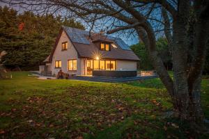 a house with the lights on in a yard at Opulent, relaxing home with Hot Tub in Fochabers