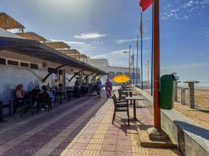 a boardwalk with tables and chairs on the beach at Apartamentos EL BARCO in Sidi Ifni