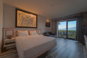een slaapkamer met een groot bed en een groot raam bij Assos Dionysos Special Class Hotel Adults Only 12 years in Behramkale