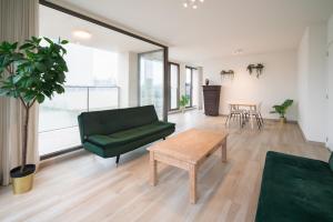 a living room with a green couch and a table at Opera Square Apartments in the Center of Antwerp in Antwerp