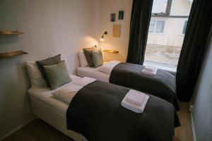 two beds in a small room with a window at Hotel Aldan - The Old School in Seyðisfjörður