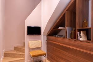 a room with a staircase with a tv and a chair at Hotel Le Placide Saint-Germain Des Prés in Paris