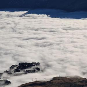 a view from an airplane of clouds over a mountain at New Gudauri Lofts by Gudauri Travel in Gudauri