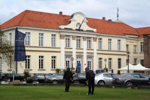 dos personas jugando golf frente a un edificio en Schlosshotel Westerholt, en Herten
