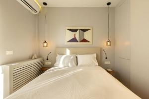Schlafzimmer mit einem großen weißen Bett mit Beleuchtung in der Unterkunft Elegant, Chic, Hip 2 BR w/ forest view in Athens! in Athen