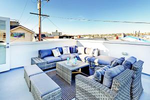 a patio with couches and a table on a balcony at Luxe Balboa Peninsula Condo w Gourmet Kitchen and Epic Rooftop Deck in Newport Beach