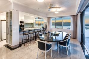 漢密爾頓島的住宿－Yacht Harbour Tower 5 - NEW Luxury and location，用餐室以及带玻璃桌和椅子的厨房