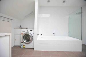 ein weißes Badezimmer mit einer Waschmaschine und einem Waschbecken in der Unterkunft Central Hobart - Beautiful Apartment in Hobart