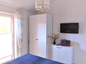 a bedroom with a white cabinet and a tv on a wall at Nordlicht in Zingst