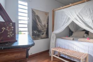 a bedroom with a canopy bed with a bench and a piano at La Kazaka Terre Sainte in Saint-Pierre