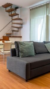um sofá cinzento numa sala de estar com uma escada em Pollicino House em Caltagirone