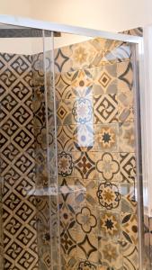 a bathroom with a tiled wall with a glass shelf at Pollicino House in Caltagirone