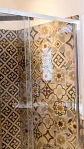 baño con pared de azulejos y estante de cristal en Pollicino House, en Caltagirone