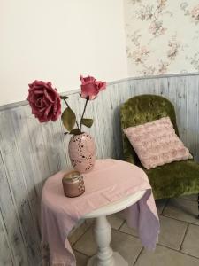 a table with a vase of flowers and a chair at EneaHouse in Fiumicino