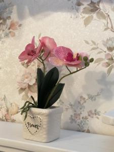 a white vase with flowers in it on a shelf at EneaHouse in Fiumicino