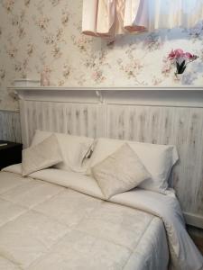 Una cama con sábanas blancas y almohadas en un dormitorio en EneaHouse, en Fiumicino