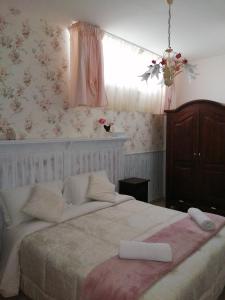 - une chambre avec un grand lit et un papier peint floral rose dans l'établissement EneaHouse, à Fiumicino