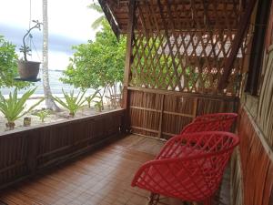2 sillas rojas en un porche con vistas al océano en Marine homestay, en Fam