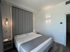 a white bedroom with a large white bed and lights at Hotel Rex in Livorno