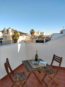einen Tisch und Stühle auf einem Balkon mit einer Flasche Wein in der Unterkunft -MalagaSunApts- City Centre SharedTerrace in Málaga