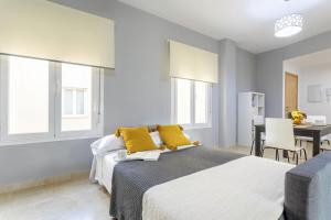 ein Schlafzimmer mit einem großen Bett mit gelben Kissen in der Unterkunft -MalagaSunApts- City Centre SharedTerrace in Málaga