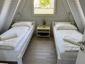 2 Betten in einem Zimmer mit einem Tisch und einem Fenster in der Unterkunft Murmel 1 - Strandkorb, Wallbox, WLan, Kamin in Carolinensiel