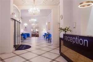 a hotel lobby with a reception sign and blue chairs at OREA Spa Hotel Palace Zvon Mariánské Lázně in Mariánské Lázně