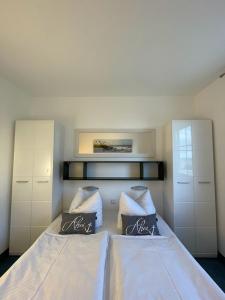 1 dormitorio con 2 camas con sábanas y almohadas blancas en Haus Svantekahs, en Glowe