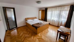 1 dormitorio con 1 cama y suelo de madera en Pensiunea Tesoro, en Corbeni