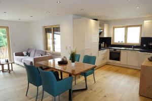 a kitchen and living room with a wooden table and blue chairs at Ferienwohnung Chalet Marienbrunnen in Oberstaufen