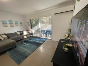 a living room with a couch and a tv at Cozy townhouse in Dakabin ideal for young family in Kallangur