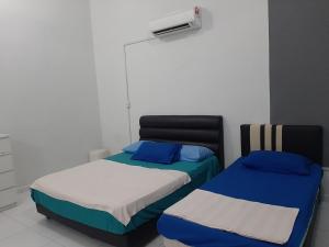 dos camas sentadas una al lado de la otra en una habitación en 5Room Home2stay Hayyan Muslim Pool, en Melaka