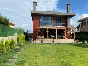 a red house with a porch and a lawn at Villa Maya in Sile