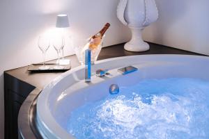 a tub filled with blue water with a candle and wine glasses at Suite1212 - Rattazzi in Monopoli +39 photos