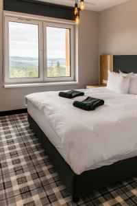 duże białe łóżko z dwoma czarnymi ręcznikami w obiekcie Kazalnica Family&Conference Resort w mieście Sosnówka