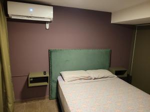 Dormitorio pequeño con cama con cabecero verde en Aqua Duplex en Villa Carlos Paz
