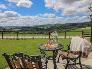 a table and chairs on a patio with a view at Shepherds View in Rhayader