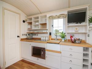 a kitchen with white cabinets and a tv at Shepherds View in Rhayader