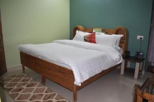 a bedroom with a bed with white sheets and pillows at Prairie Lodge in Shimla