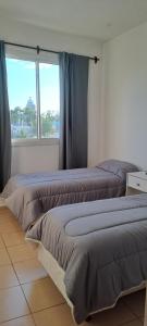 two beds in a room with a window at Sol y Malbec Departamentos in Guaymallen +3 photos