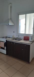 a kitchen with a stove and a sink and a window at Sol y Malbec Departamentos in Guaymallen