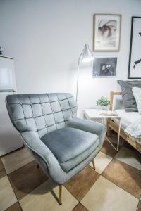 a blue chair in a living room with a bed at LION apartments - Your own apartment in Cracow in Krakow
