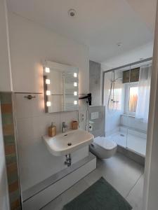 a white bathroom with a sink and a toilet at FineApartment Borgstedt in Borgstedt