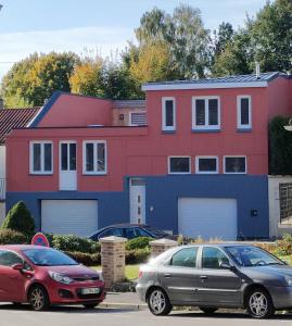 twee auto's geparkeerd voor een kleurrijk huis bij L'Atelier in Saint-Laurent-Blangy