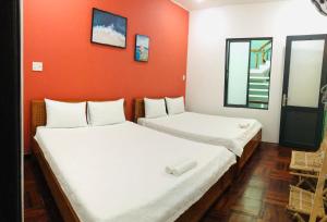 Duas camas num quarto com uma parede laranja em NẮNG HOMESTAY em Tuy Hoa
