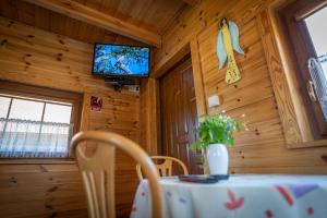 a dining room with a table and a tv in a cabin at Osada Koszałkowo Wieżyca in Szymbark