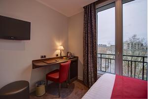 a hotel room with a desk and a bed and a window at Hôtel Du Midi Paris Montparnasse in Paris