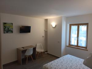 a bedroom with a bed and a desk and a window at Gufo Depandance in Bormio