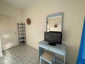 a room with a television on a desk with a mirror at Tersanas Beach Apartments in Chorafakia