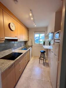 a kitchen with wooden cabinets and a sink and a stool at Mas Pinell 3 -Viu bé in L'Estartit